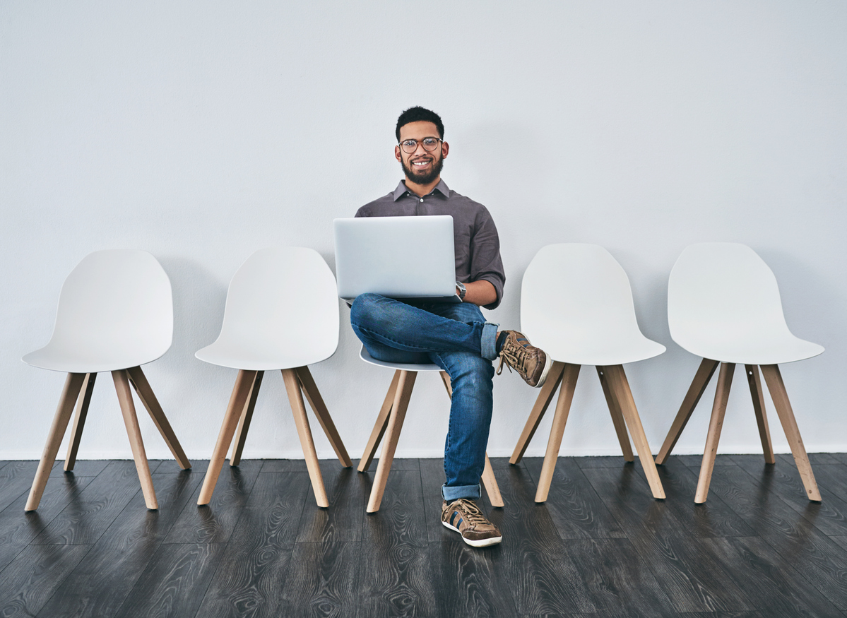 Freundlicher Bewerber mit Laptop in Stuhlreihe